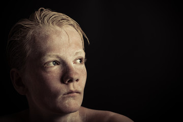 Suspicious blond boy stares into the light