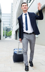 Successful adult man in suit with suitcase is is meeting his partner