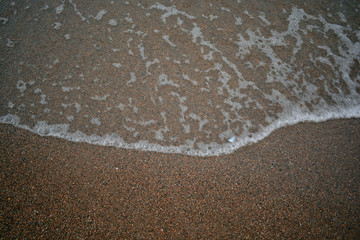 Waves with foam against the background of sand
