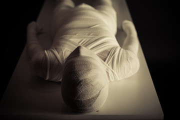 Young mummy displayed on table in darkness