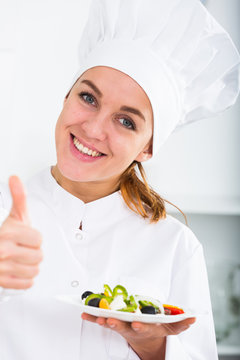 portrait of young coosie woman showing salad at kitchen