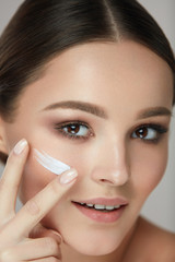 Facial Care. Closup Beautiful Woman Putting Skin Cream On Face