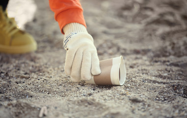 Volunteer picking up litter from sand, closeup