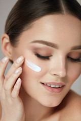 Facial Care. Closup Beautiful Woman Putting Skin Cream On Face