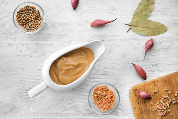 Sauce boat with turkey gravy and spices on wooden table