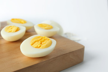 Cutting board with hard boiled eggs on white background. Nutrition concept