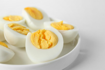 Ceramic tray with sliced hard boiled eggs on white background. Nutrition concept
