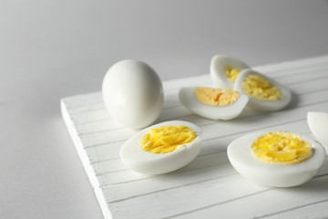 White cutting board with sliced hard boiled eggs on grey background. Nutrition concept