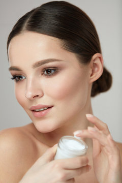 Face Beauty Care. Woman With Natural Makeup Holding Cream
