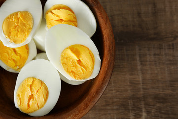 Bowl with sliced hard boiled eggs on wooden table. Nutrition concept