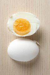 Sliced hard boiled egg in shell on wooden surface. Nutrition concept