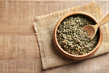 Bowl with boiled lentils, spoon and napkin on wooden table