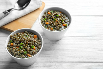 Composition with tasty lentil dish on light wooden table