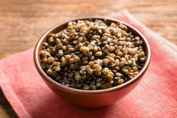 Bowl with tasty lentil porridge and napkin on table, closeup