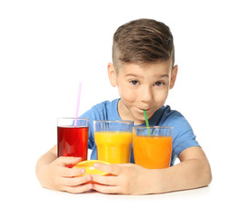 Cute little boy with glasses of different juice on white background