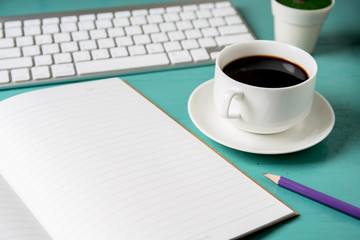 office table with notebook, computer keyboard, cup of coffee and notebook copy space