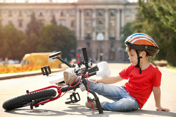 Cute little boy fallen off his bicycle outdoors