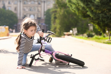 Cute little girl fallen off her bicycle outdoors