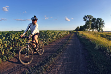 Fototapeta na wymiar smiling cyclist rides along a field trail.