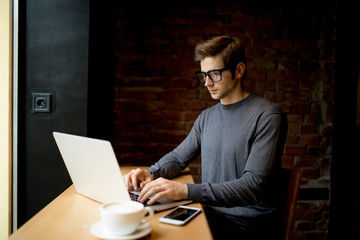 Businessman using laptop on wooden table in coffee shop with a cup of coffee