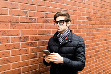 Typing text message side view of handsome young man in smart casual wear holding mobile phone