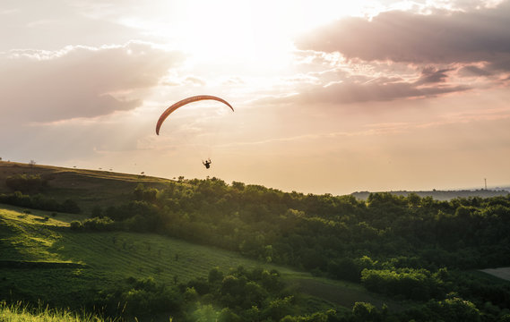 Paraglider in sunset, over beautiful hills and vineyards 