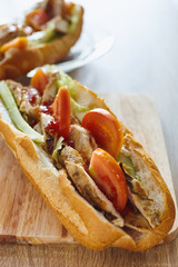 French bread sandwich with chicken and vegetables on the wooden table
