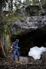 Young man hiking in scandinavia landscape. Rocks hidden in the forest. Karelia outdoors travel destination.