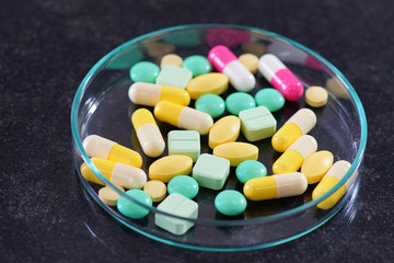 Pharmaceutical medicine pills in petri dish on table