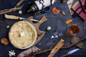 Snack of pancakes topped with butter and glass of wine on wooden table