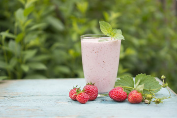 Fresh pink smoothies made from strawberries and raspberries on a natural background on a wooden table.