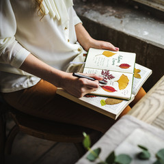 Hands Writing Detail of Dried Flowers Collection in Notebook Handmade Work Hobby