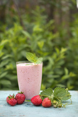 Fresh pink smoothies made from strawberries and raspberries on a natural background on a wooden table.
