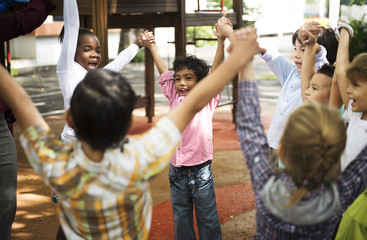 Group of diverse kindergarten students standing holding hands together