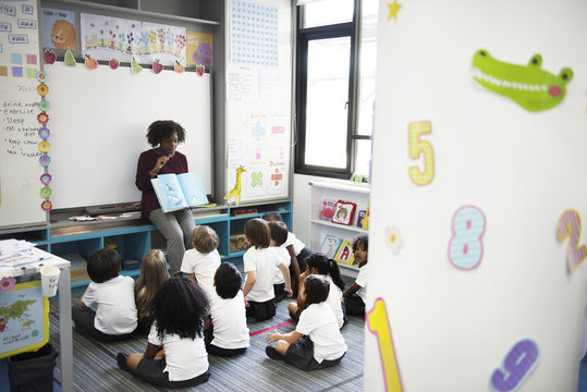 Kindergarten students sitting on the floor listening to story telling