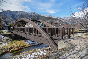 Fototapeta na wymiar Wooden bridge across tha canal near Kawaguchi lake and Fuji mountian in late winter of Yamanashi prefecture, Japan