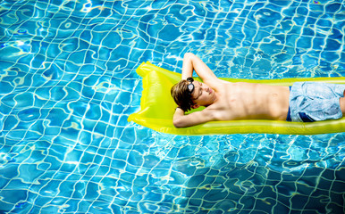 Young caucasian boy enjoying floating in the pool with tube © Rawpixel.com