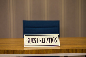 The sign with guest relation inscription is on the table. Guest accommodation in the hotel. A table...