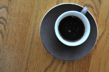 A cup of coffee stands on a brown table in a cafe. A cup of beautiful and fragrant latte with a slice of sugar - a refined sugar and tubules is on the table in a cafe. Cafe inside with visitors and la