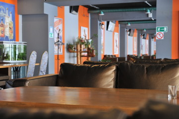 A cup of coffee stands on a brown table in a cafe. A cup of beautiful and fragrant latte with a slice of sugar - a refined sugar and tubules is on the table in a cafe. Cafe inside with visitors and la