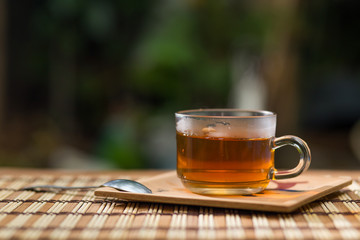 Glass cup of tea, teaspoon on wooden table.