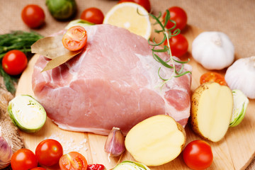 Raw pork on cutting board and vegetables 