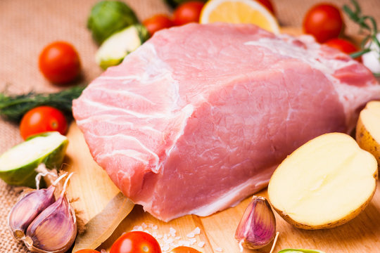 Raw pork on cutting board and vegetables 