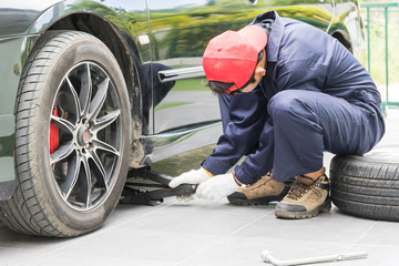 Mechanic replacing lug nuts changing tires on vehicle