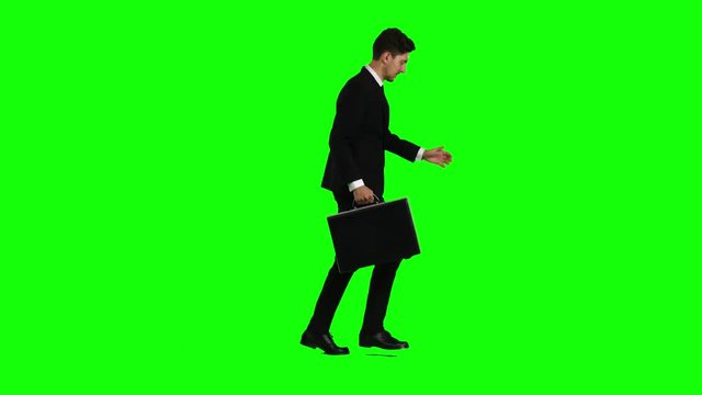 Man holds a briefcase in his hand, he rushes over it. Green screen