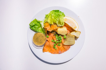 Marinated salmon with green salad on the dish isolated on white background from top-view