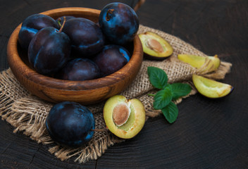 Bowl with  plums with green leaves