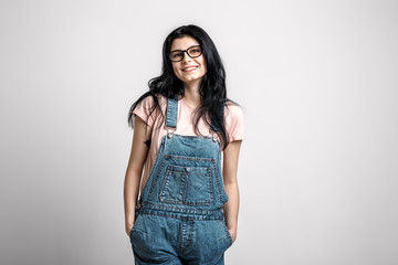 Portrait of smart beautiful brunette girl in eyeglasses with natural make-up, on grey background.