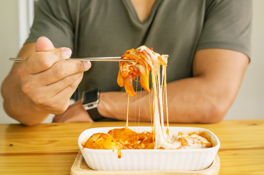 Man eating cheese Tokboki (Korean hot and spicy rice cake) in a canteen.
