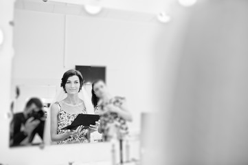 Fototapeta na wymiar Beautiful bride getting ready for her wedding in a makeup and hair beauty salon. Black and white photo.